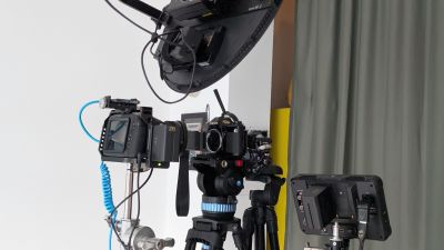 A digital cinema camera set up facing an analogue photo camera with the lens removed.