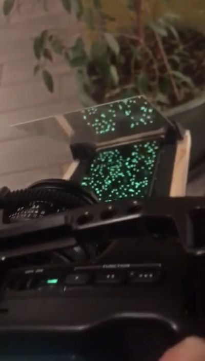 A photo showing how the pepper\'s ghost effect: the green dots on the phone screen are reflected by the acrylic sheet, overlaying them on the camera\'s view.